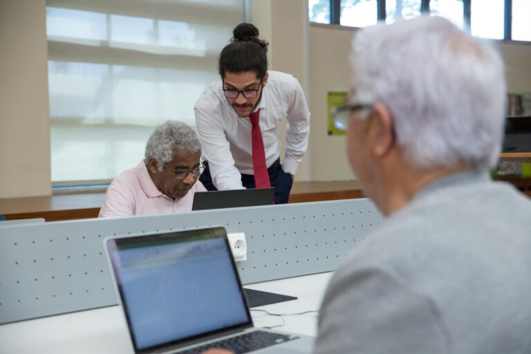Elderly individuals studying with a tutor in a modern library setting.